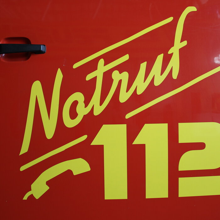 Notruf 112 an der Tür eines Feuerwehrautos